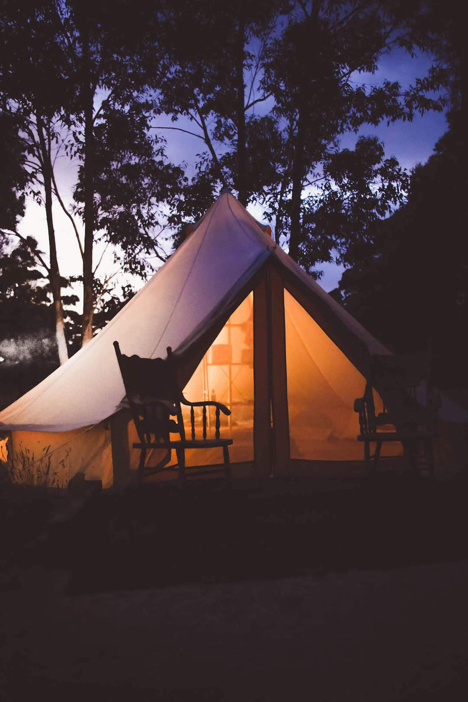 Glamping stan zářící v podvečer mezi stromy